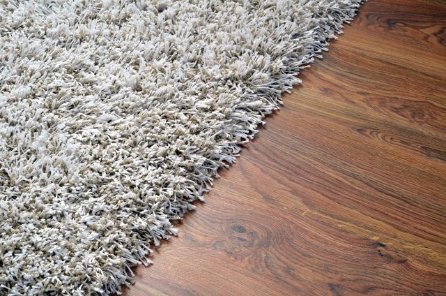 White shaggy carpet on brown wooden floor detail